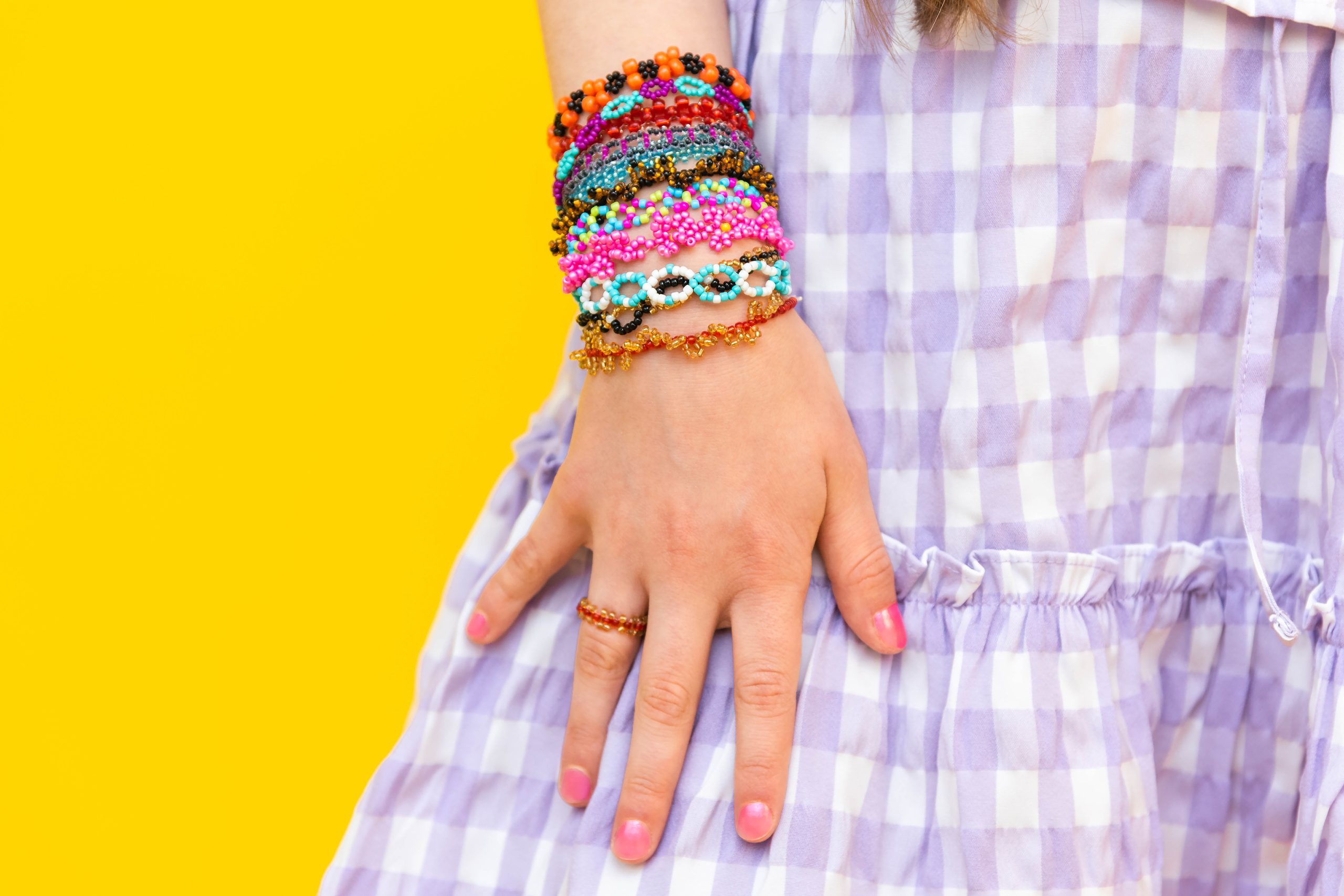Beaded bracelets on the hands of a little girl. Multicolored jewelry on his hands. Beading for children.