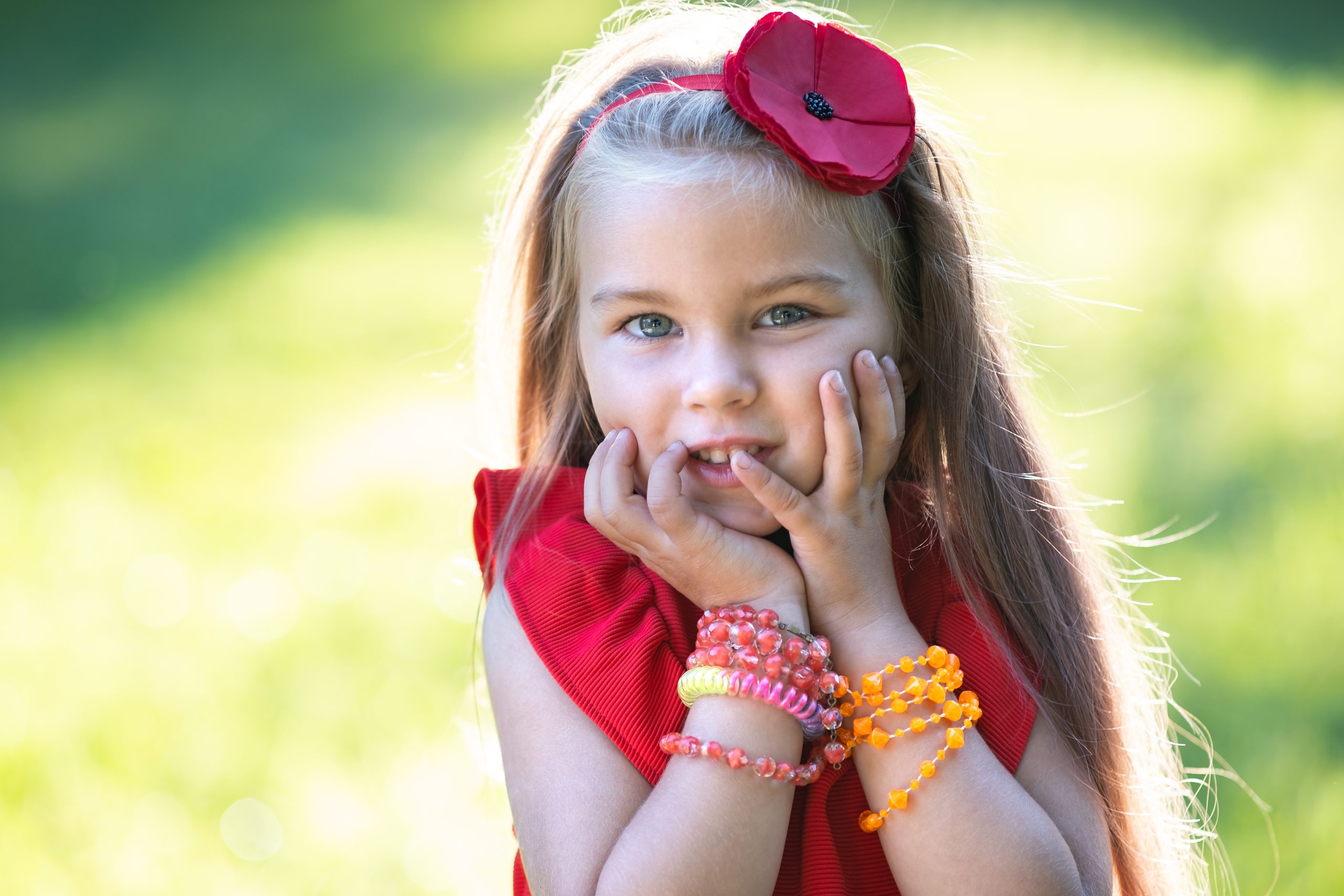 Portrait of pretty fashionable child girl in red dress enjoying warm sunny summer day.